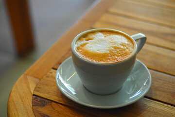 Warm cup of coffee on wooden table at cozy cafe