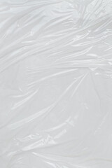 Closeup of crumpled, reflective clear plastic ideal for abstract designs, backgrounds, textures, and environmental or ecofriendly concepts in graphic design.