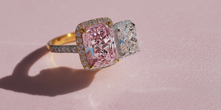 Stunning Toi et Moi engagement ring featuring pink and white diamond set in gold band with intricate detailing, casting shadow on soft pink surface
