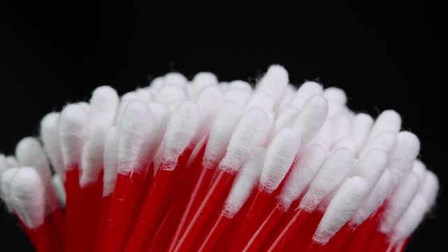 Cotton swabs in bag rotating, cotton buds on black background cloe up. Personal hygiene and cosmetic items. Ear cleaning q-tips