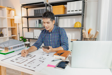 A young architect works on house design plans at his desk, focusing on drawings and scale models. The scene conveys creativity, dedication, and precision in modern architecture projects.