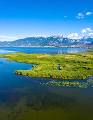 Aerial view of a lake surrounded by mountains and lush green marshland