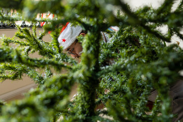 Man decorates a Christmas tree, surrounded by lush greenery and festive beads, exuding happiness and holiday cheer in a close and intimate setting.