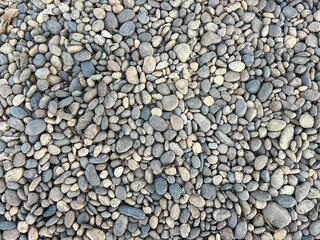 A tightly packed surface of smooth, rounded pebbles in varying sizes and shades of gray, creating a natural stone texture.