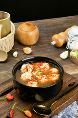 Jumbo meatball soup and spicy meatball cuanki in a round bowl with a brown wooden background