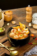 Jumbo meatball soup and spicy meatball cuanki in a round bowl with a brown wooden background
