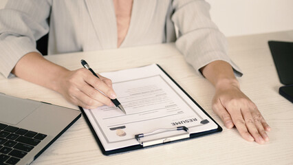 Businesswoman sits and evaluates resume and evaluates. Views resume of job applicant. Recruitment concept