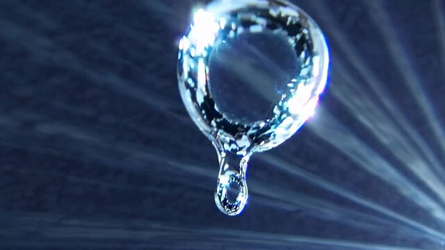 Clear liquid sparkles, forming intricate circular patterns and delicate droplets that swirl and reshape in a weightless, ethereal dance against a vibrant deep blue background
