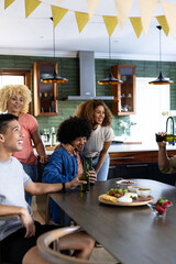 Friends laughing and enjoying drinks together in modern kitchen setting