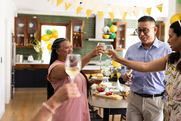 At home, diverse group of seniors toasting with wine glasses, celebrating together
