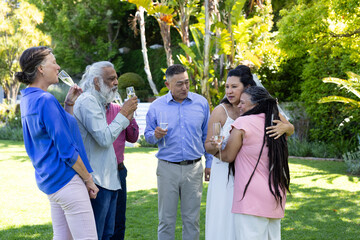 Celebrating outdoors, seniors sharing drinks and joyful moments together in garden