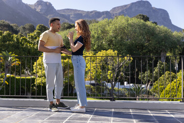 Fototapeta premium Young couple enjoying conversation on sunny balcony with scenic mountain view