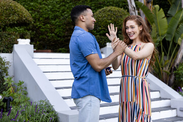 Young couple joyfully celebrating engagement outdoors, holding hands and smiling