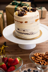Tall cake with chocolate decorations on table surrounded by gifts and snacks