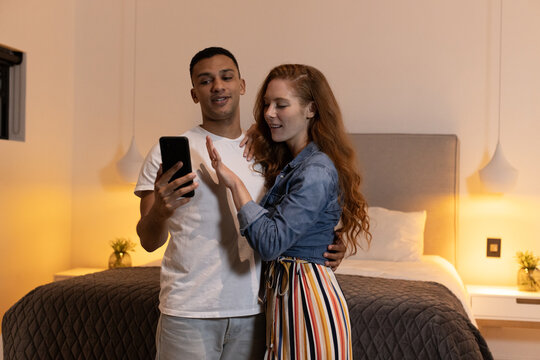 Young couple at home sharing joyful moment while looking at smartphone