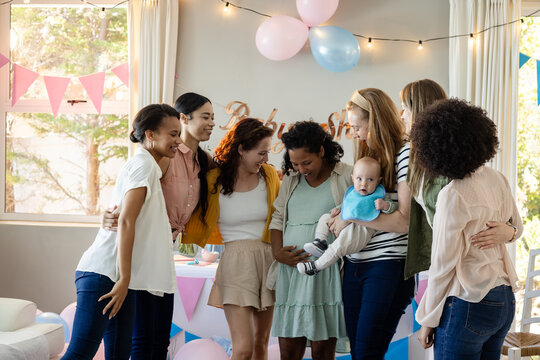 Group of diverse women celebrating baby shower with joy and laughter at home