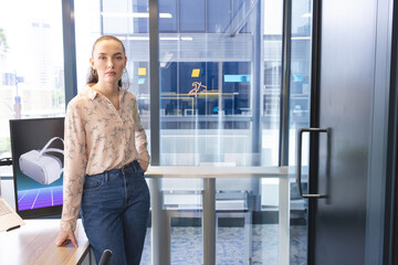 Confident woman standing in modern office with VR headset on desk, copy space
