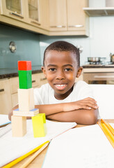 Smiling African American boy playing with colorful blocks at home kitchen table