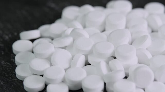 Sugar substitute tablets rotating on black surface macro. Artificial sweetener pills zero calories