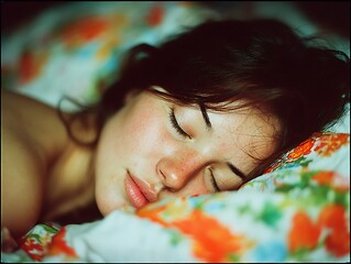 Dreamscape: A peaceful woman is captured in a serene sleep, her face bathed in soft, natural light, surrounded by the comforting embrace of a floral-patterned bed. 