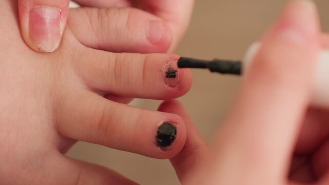 Close view of student hands gently applying black nail polish to toes, careful brush strokes, home pedicure moment, soft light, clean grooming focus, relaxed pace, attention to detail on tiny toenail