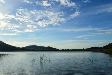 Landscape view of a lake surrounded by forested hills with cloudy sky