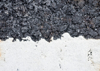 Close-up of a wall with white paint and black coal.