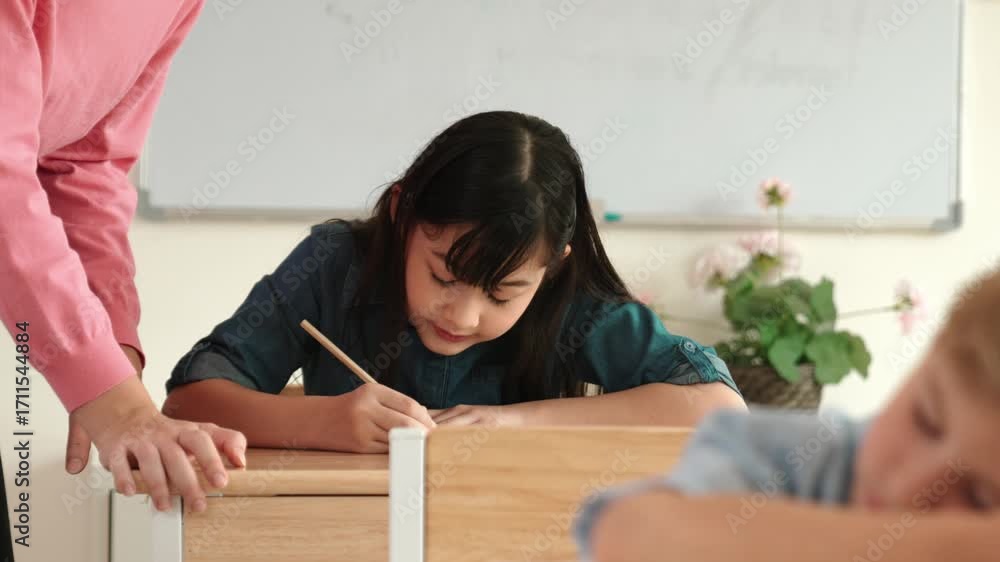 Poster asian girl writing or taking a note while teacher checking classwork. caucasian teacher help happy s