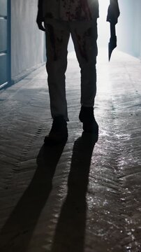 Bloody man in white pajamas holding axe walking slowly in dark haunted corridor with fog and flickering ceiling light cinematic horror slow motion Halloween scary atmosphere thriller