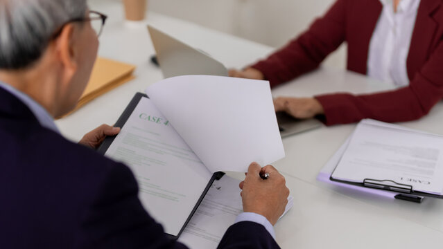 Legal professionals review case documents office setting for compliance and consultation Adult Asian man lawyer examines files