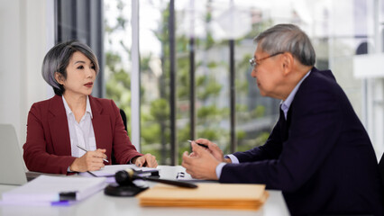 Adult Asian legal professionals discuss complex case details office meeting providing expert counsel reviewing documents offering client advice