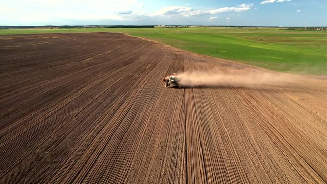 Soil tillage, Cultivated land. Tractor with disc cultivator on Sowing grain. Agricultural tractor on Seeds sowing on farm field. Tractor disk harrow on plowing field. Soil cultivation, aerial view.