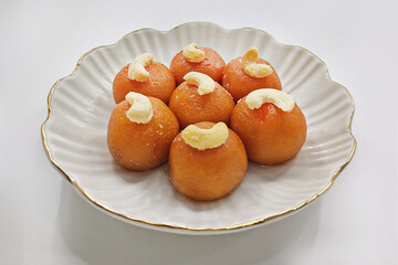 Traditional Indian Sweet Balls with Cashew Topping on an Elegant White Plate