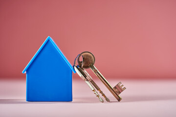blue house model and house key against pink background