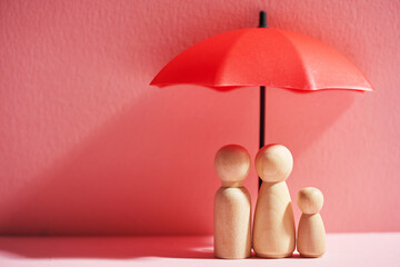 Umbrella and wooden dolls with copy space. Family protection and insurance coverage concept.