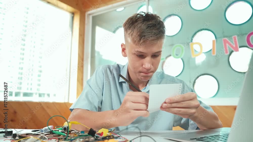 Poster smart happy boy inspect or learning to use electronic tool while taking a note. high school student 