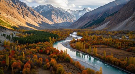 Breathtaking autumn valley landscape with a winding river, vibrant fall foliage, and majestic snow-capped mountains under a dramatic sky.