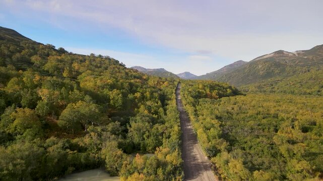 Autumn dirt road through Viluchinsky Pass, Kamchatka. Slopes with colorful vegetation. 825 m pass southwest of Petropavlovsk-Kamchatsky in South Kamchatka Nature Park.