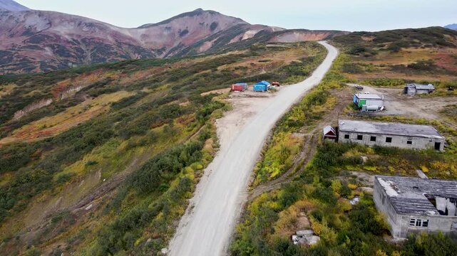 Autumn dirt road through Viluchinsky Pass, Kamchatka. Slopes with colorful vegetation. 825 m pass southwest of Petropavlovsk-Kamchatsky in South Kamchatka Nature Park.