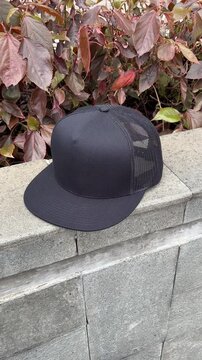 Black mesh snapback cap outdoors with camera moving from right to left