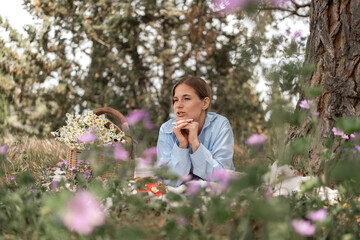 Fototapeta premium Picnic Flowers Woman: Woman relaxes in nature with flowers, enjoying calm summer picnic outdoor.