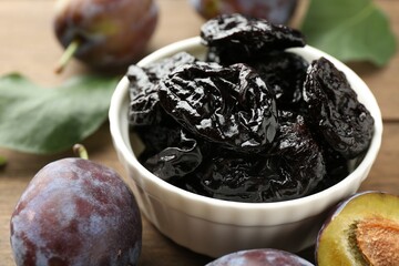 Dried prunes, fresh plums and green leaves on table, closeup