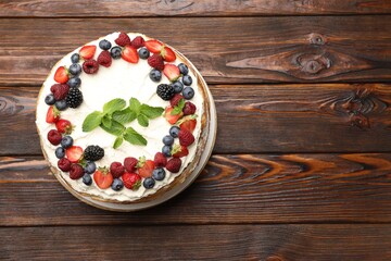 Delicious crepe cake with fresh berries on wooden table, top view. Space for text
