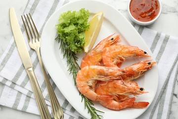 Tasty grilled shrimps served with lemon, lettuce, rosemary and sauce on white marble table, flat lay. Delicious seafood dish