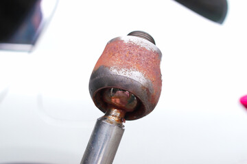 Rusty worn-out automotive inner tie rod with ball joint close-up, showing corrosion and metal wear on suspension steering component, essential for vehicle safety, handling, and alignment maintenance