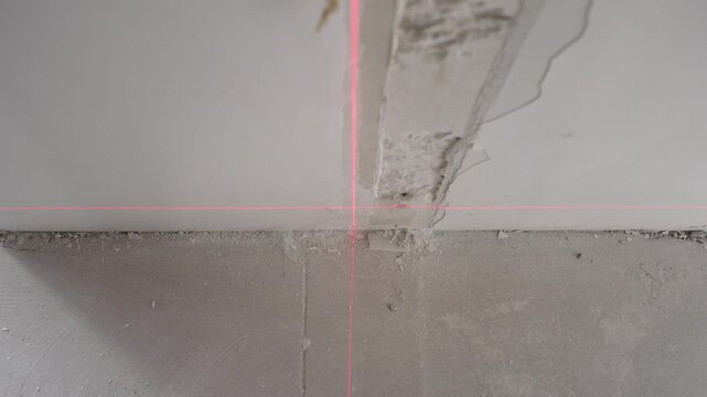 Precise red laser level projecting horizontal and vertical lines for alignment. The measurement tool is used during construction or renovation