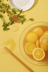 Lemon bowl with honey and mint on yellow background