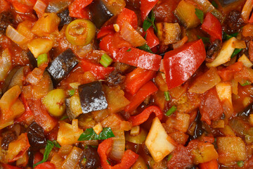 A top-down macro view of a rustic Italian caponata, a delicious stew of eggplant, bell peppers, tomatoes, and other vegetables