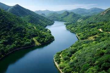 Fototapeta premium Serene mountain river landscape with lush green forests under clear blue sky