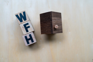 Wooden cubes with texting message WFH with wood home. Commonly used to represent work from home.